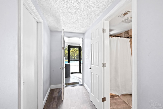 hall with hardwood / wood-style floors and a textured ceiling