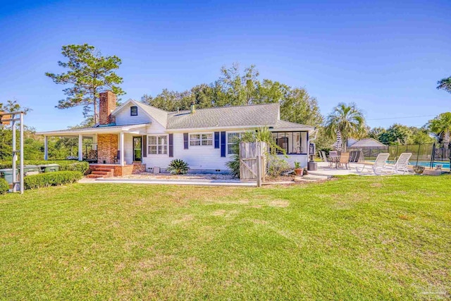 rear view of house featuring a yard, a patio area, and a swimming pool