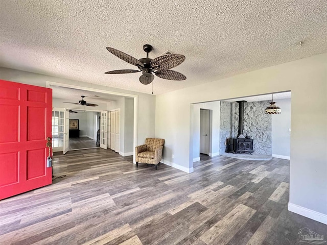 941 Summer Shade Ln, Cantonment, FL 32533 - unfurnished room featuring wood finished floors, a textured ceiling, a wood stove, baseboards, and a ceiling fan