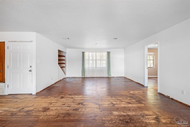 empty room featuring a textured ceiling and dark wood-type flooring