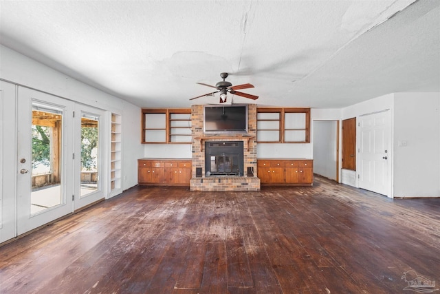 unfurnished living room featuring a textured ceiling, dark hardwood / wood-style floors, a brick fireplace, and ceiling fan