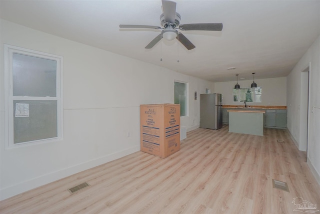 unfurnished living room with ceiling fan, light hardwood / wood-style flooring, and sink