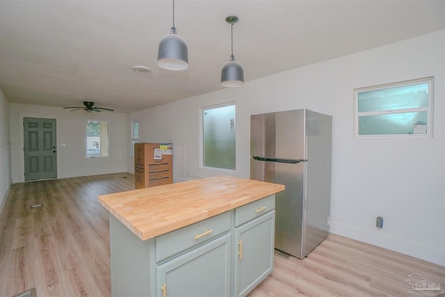 kitchen featuring stainless steel refrigerator, light wood-type flooring, pendant lighting, a kitchen island, and butcher block countertops