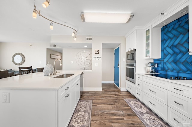 kitchen with an island with sink, dark wood-type flooring, stainless steel appliances, sink, and white cabinetry