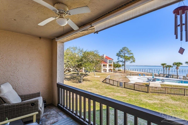 balcony featuring a water view and a ceiling fan