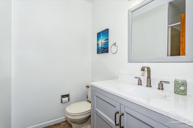 bathroom with toilet, baseboards, and vanity