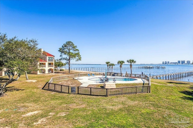 pool featuring a water view, a lawn, and a patio