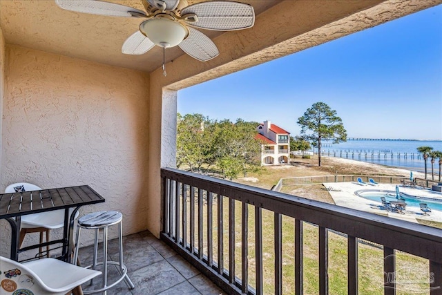 balcony with a water view and a ceiling fan