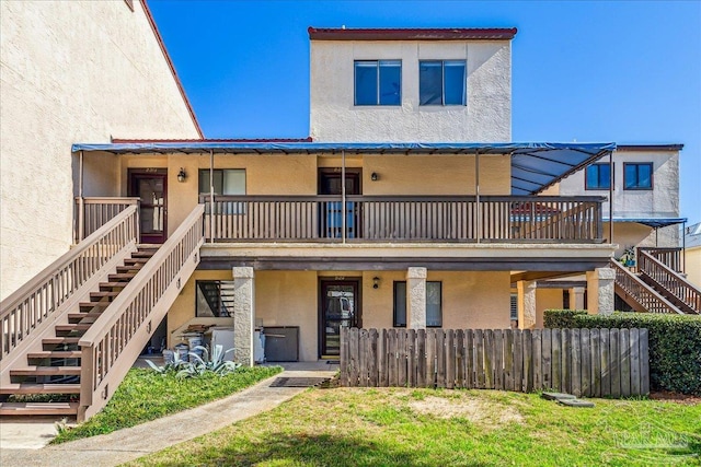 view of front of house with fence, stairway, and stucco siding