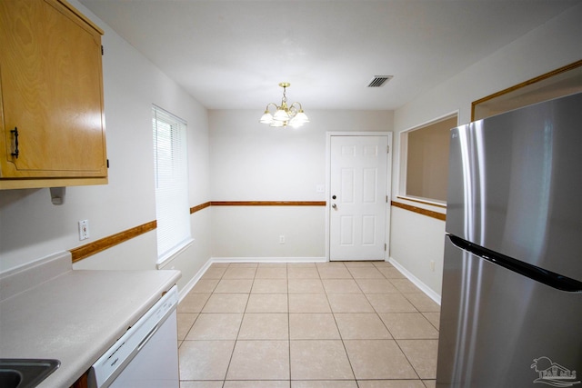 kitchen with white dishwasher, a notable chandelier, light tile patterned floors, pendant lighting, and stainless steel fridge