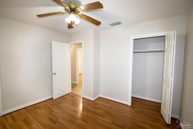 unfurnished bedroom with wood-type flooring, ceiling fan, and a closet