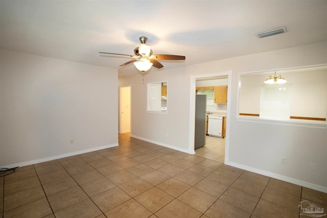 tiled spare room with ceiling fan with notable chandelier