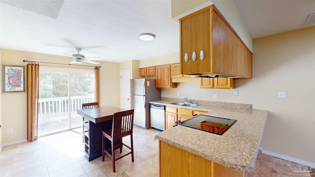 kitchen with sink, ceiling fan, appliances with stainless steel finishes, a kitchen breakfast bar, and a center island