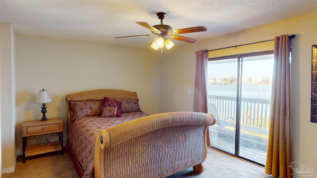 bedroom with a water view, carpet flooring, access to exterior, and a textured ceiling