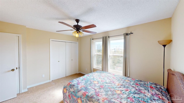 carpeted bedroom featuring ceiling fan, a closet, and a textured ceiling