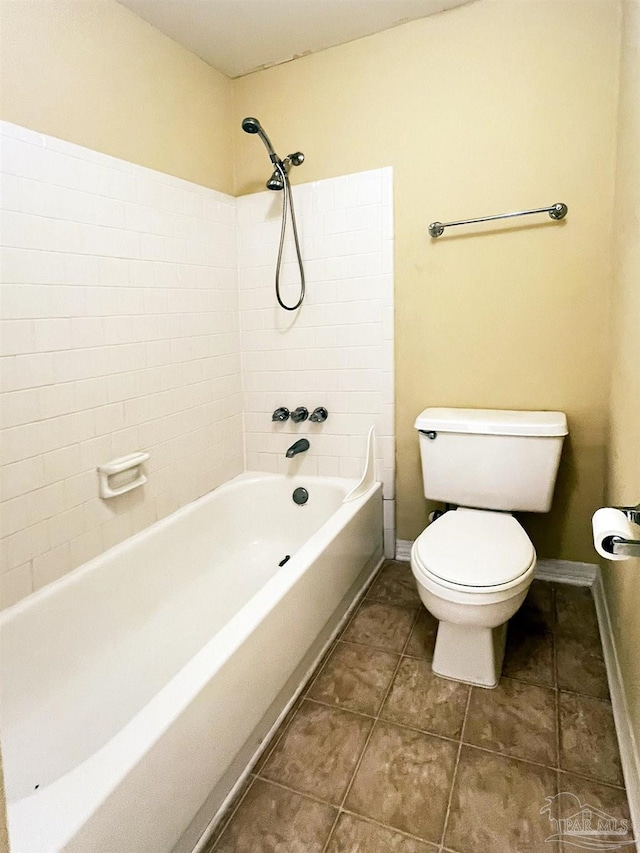 bathroom with tile patterned flooring, tiled shower / bath, and toilet