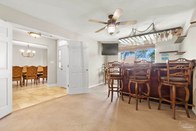 dining area featuring baseboards, light tile patterned flooring, a bar, and ceiling fan with notable chandelier