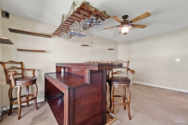 bar with a ceiling fan and baseboards