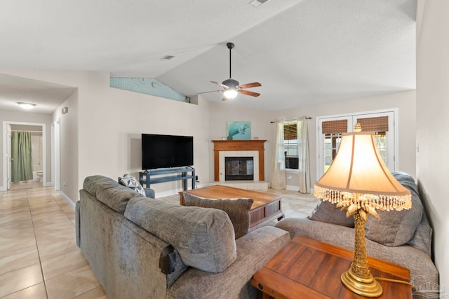 living room featuring baseboards, a ceiling fan, a tile fireplace, lofted ceiling, and light tile patterned flooring