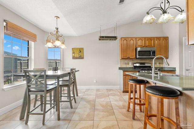 dining space featuring light tile patterned floors, visible vents, vaulted ceiling, a textured ceiling, and baseboards