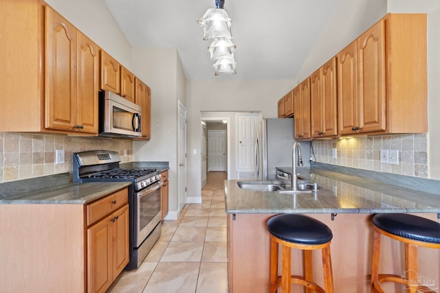 kitchen with stainless steel appliances, decorative backsplash, a sink, a peninsula, and a kitchen bar