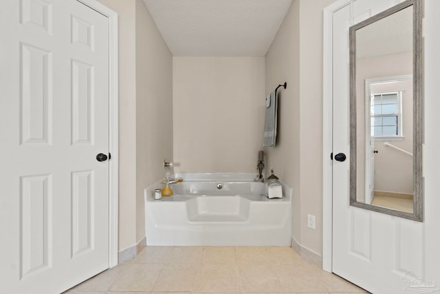 bathroom featuring a textured ceiling, baseboards, a bath, and tile patterned floors