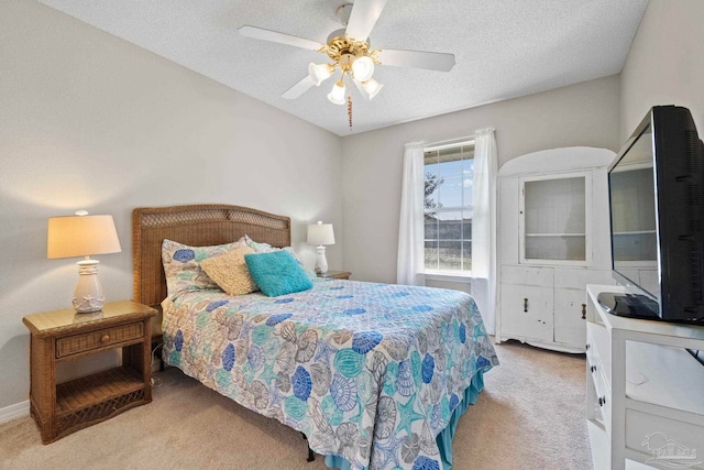 bedroom featuring a ceiling fan, light colored carpet, and a textured ceiling