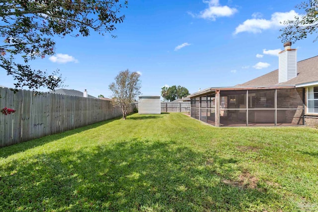 view of yard with an outbuilding, a storage shed, a fenced backyard, and a sunroom