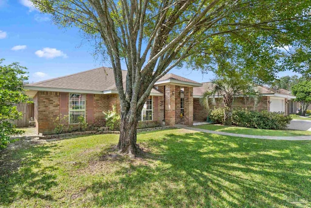 single story home featuring an attached garage, brick siding, a front yard, and fence