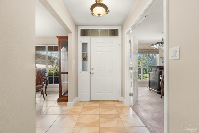 foyer entrance with light carpet, baseboards, and light tile patterned flooring