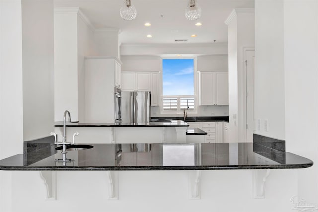 kitchen with sink, kitchen peninsula, white cabinetry, stainless steel refrigerator, and dark stone counters