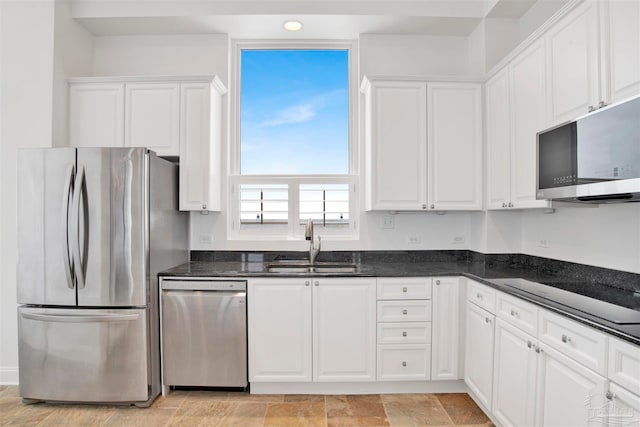 kitchen with white cabinets, appliances with stainless steel finishes, sink, and dark stone counters