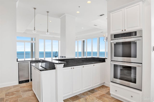 kitchen featuring white cabinets, kitchen peninsula, double oven, and a wealth of natural light