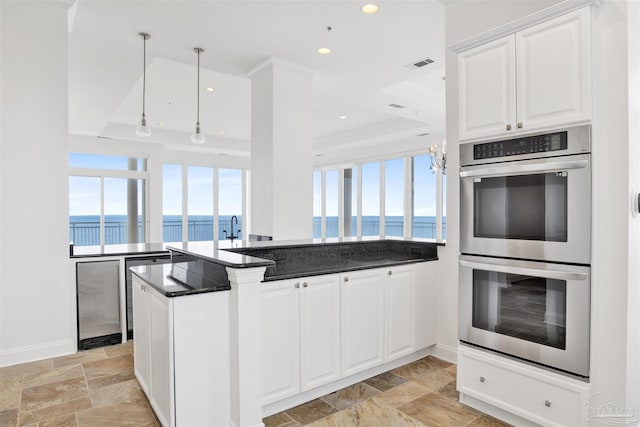 13555 Sandy Key Dr Ph, Ph, Perdido Key, FL 32507 - kitchen featuring double oven, stone finish floor, white cabinetry, a water view, and baseboards