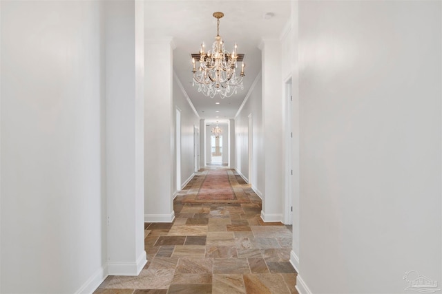 hallway with ornamental molding and an inviting chandelier