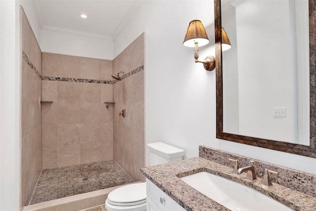 bathroom featuring ornamental molding, tiled shower, vanity, and toilet