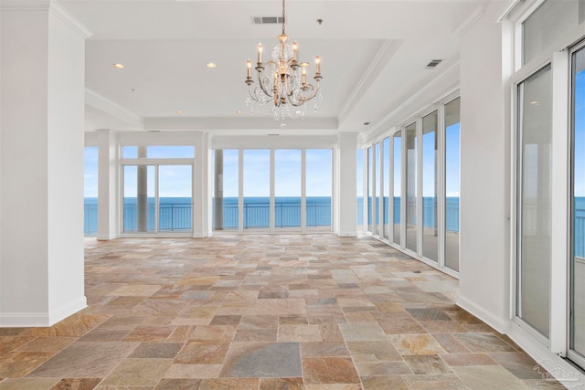 interior space featuring an inviting chandelier, a raised ceiling, crown molding, and a water view