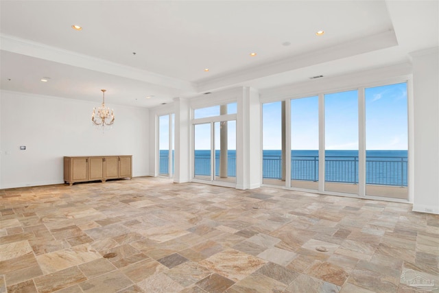 unfurnished room with a raised ceiling, crown molding, a chandelier, and a water view