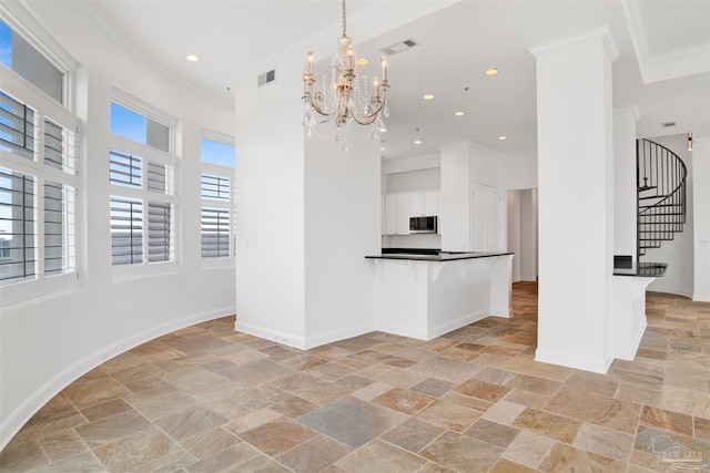 kitchen with a kitchen breakfast bar, white cabinets, pendant lighting, crown molding, and an inviting chandelier