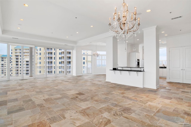 unfurnished living room featuring crown molding and a chandelier