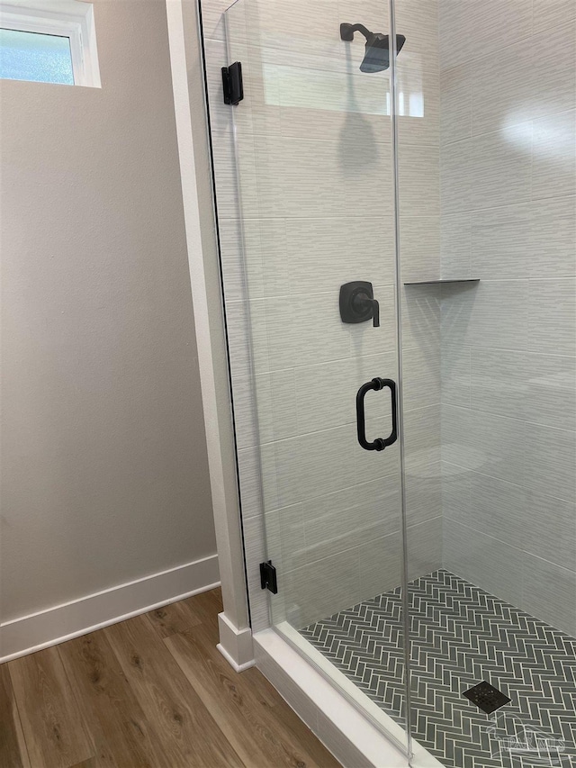 bathroom with wood-type flooring and a shower with door