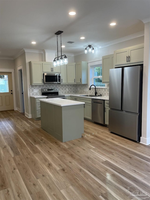 kitchen featuring appliances with stainless steel finishes, sink, backsplash, hanging light fixtures, and a center island