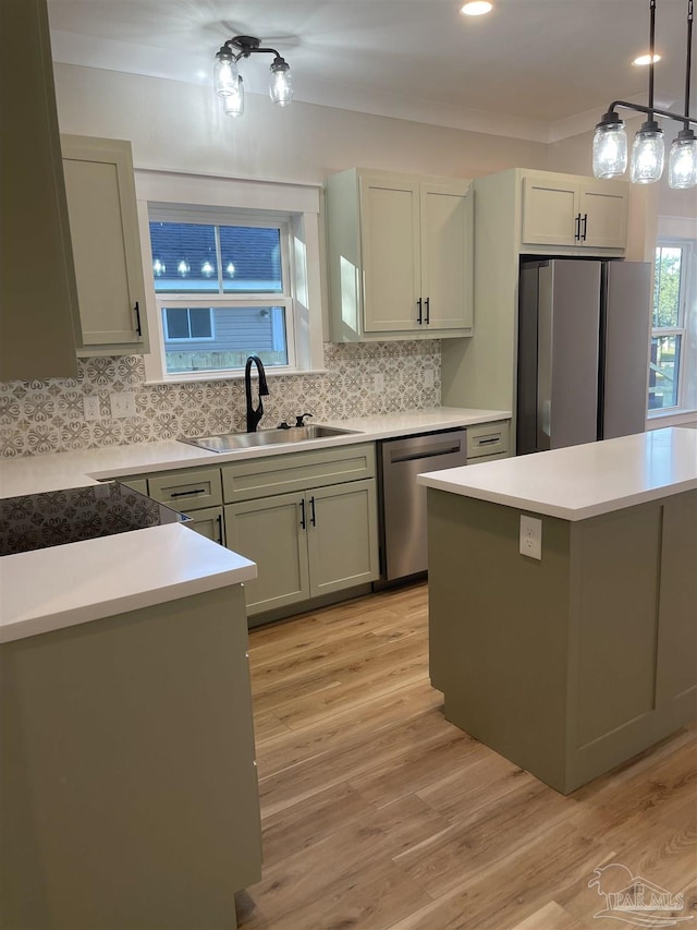 kitchen with pendant lighting, sink, light hardwood / wood-style flooring, backsplash, and stainless steel appliances