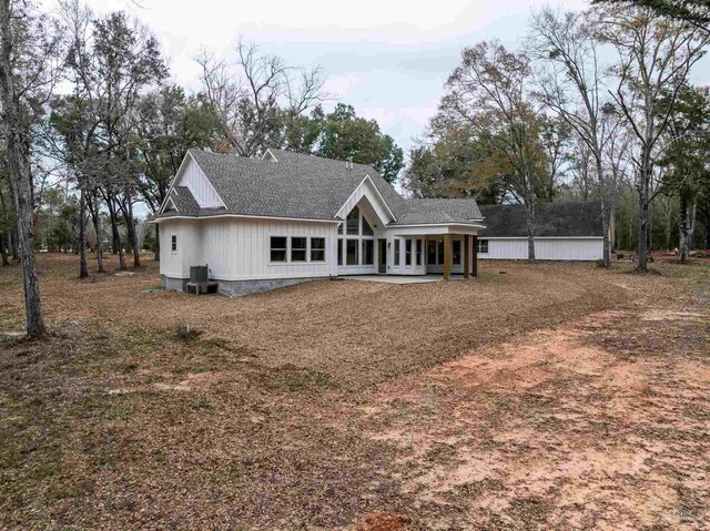 back of property featuring a sunroom, central AC unit, and roof with shingles