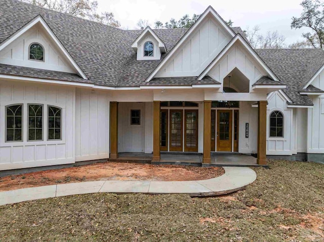 view of front facade with a porch, roof with shingles, and board and batten siding