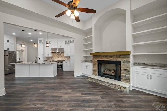 unfurnished living room featuring a fireplace, recessed lighting, dark wood-style floors, and a sink