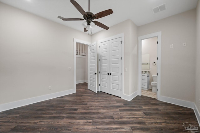 unfurnished bedroom with baseboards, visible vents, dark wood-type flooring, a closet, and connected bathroom