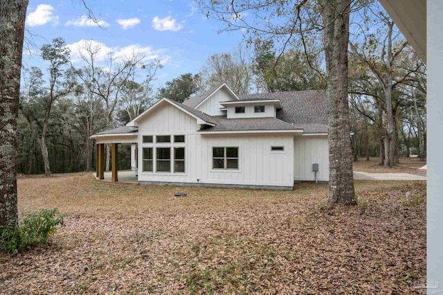 back of property with board and batten siding and a shingled roof