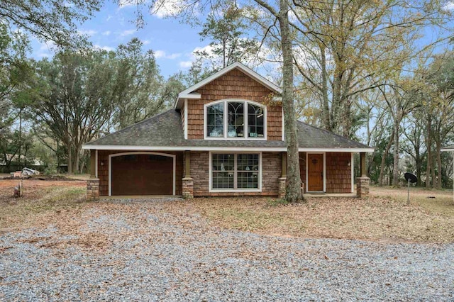 view of front of property with stone siding, driveway, an attached garage, and a shingled roof