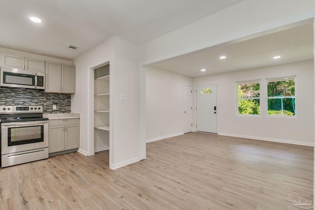 kitchen featuring gray cabinetry, decorative backsplash, light hardwood / wood-style flooring, and appliances with stainless steel finishes